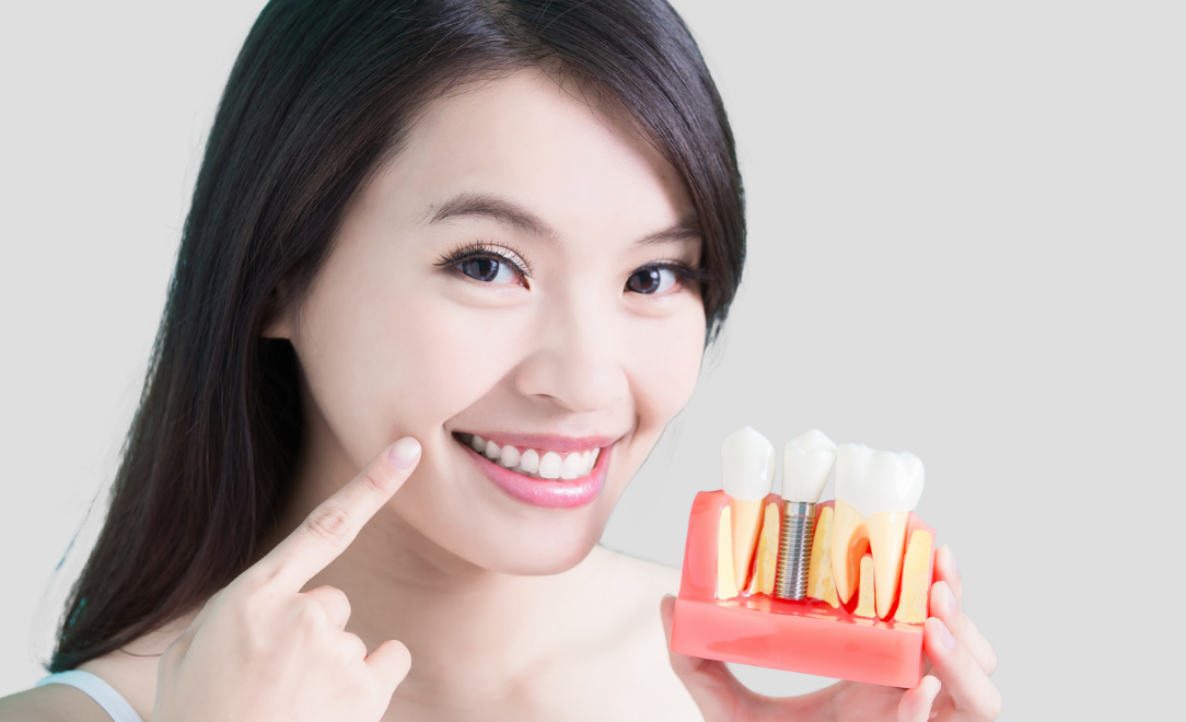 Happing patient smiling, holding model of dental implants